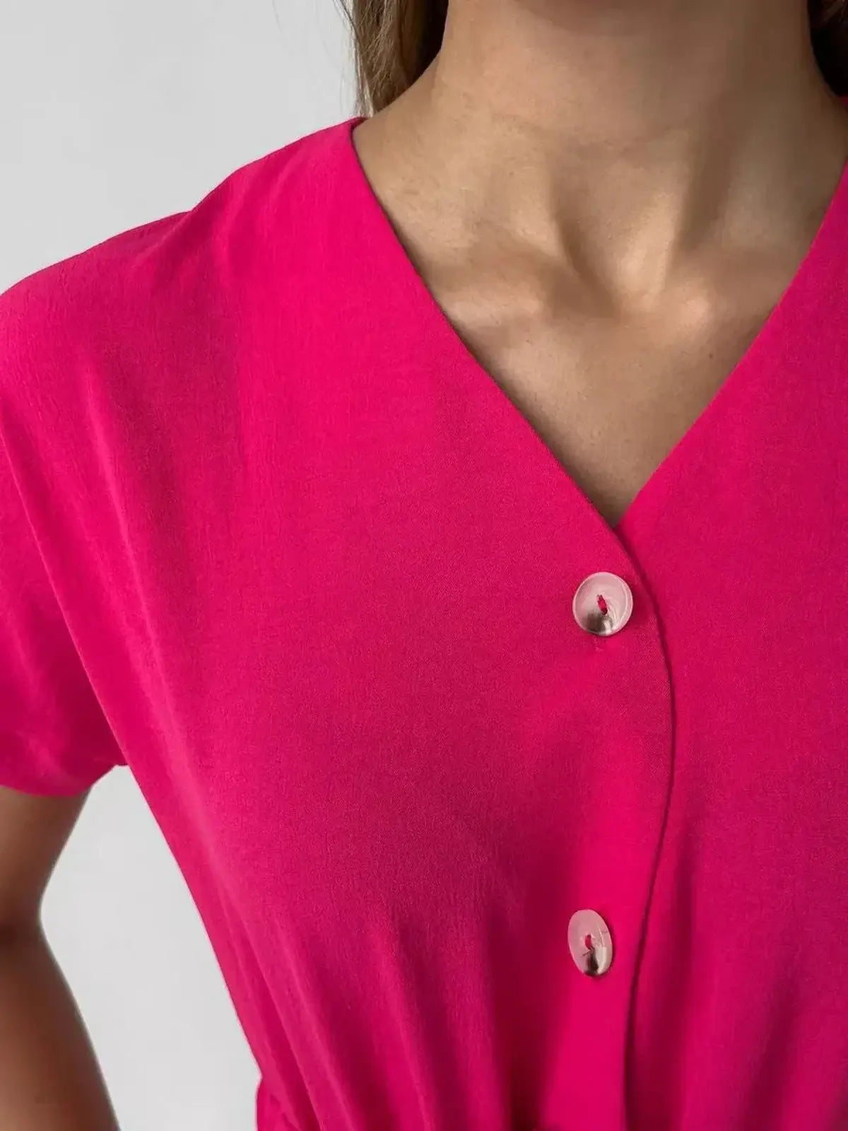 Close-up of Radiance Midi Dress in vivid fuchsia showing V-neckline and button-front details, ideal for summer styling.