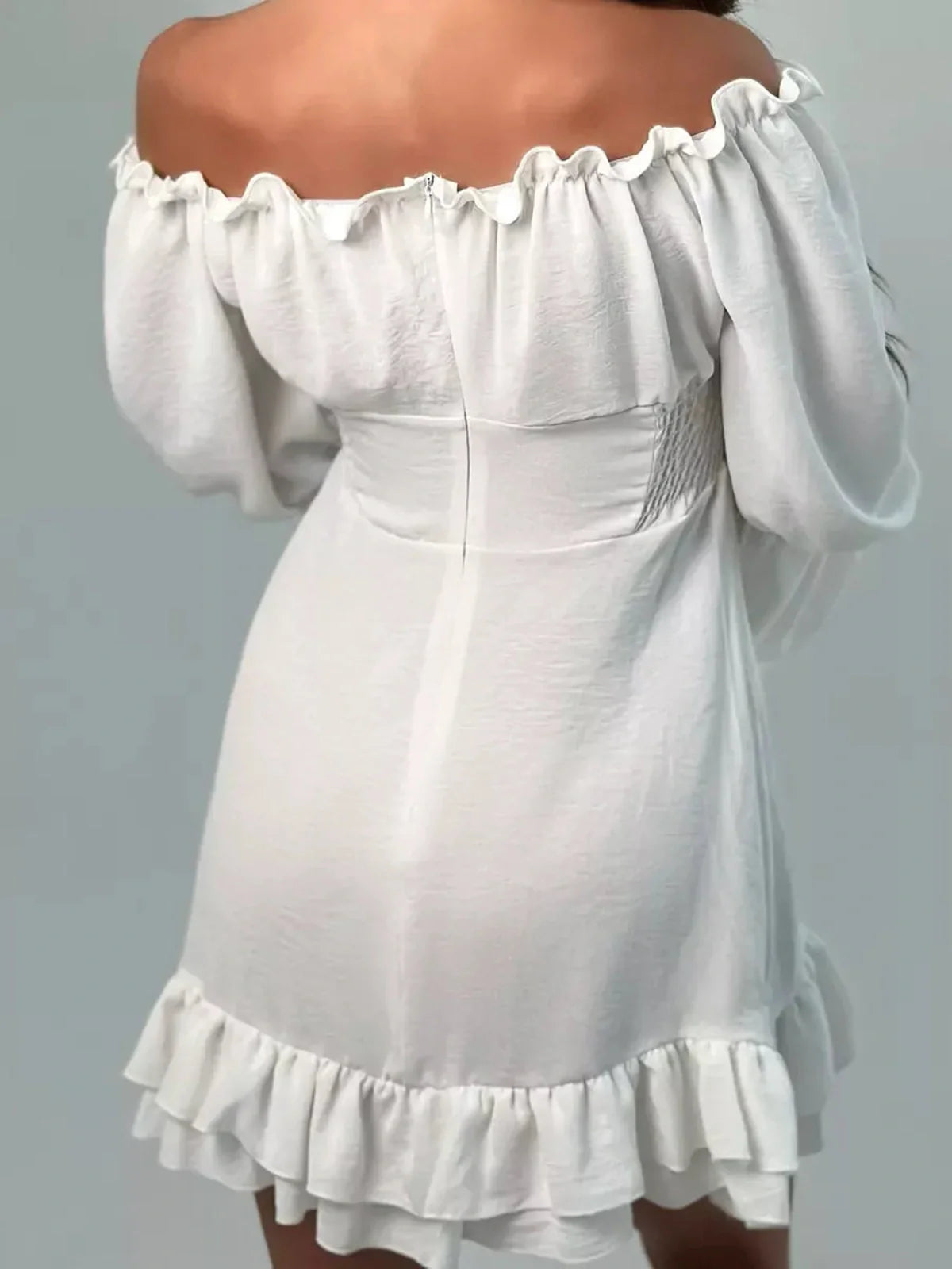 Back view of the Ruffle Bloom Mini Dress showcasing off-shoulder design and flowy ruffles in warm white fabric.
