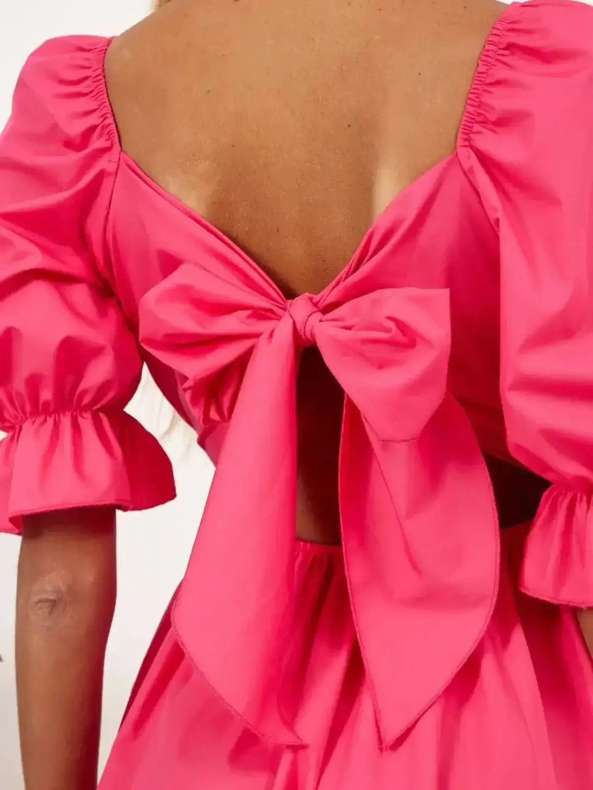 Back view of a pink dress featuring a stylish bow and puff sleeves, perfect for summer parties and weddings.