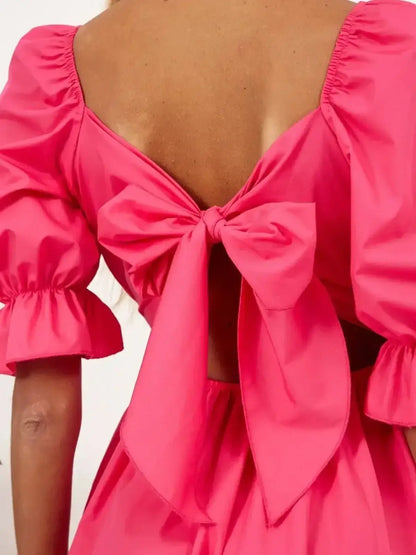 Back view of a pink dress featuring a stylish bow and puff sleeves, perfect for summer parties and weddings.