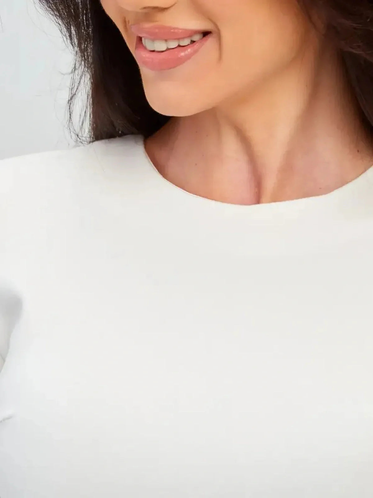 Close-up of a woman smiling, showcasing the elegant neckline of the Ivory Sculpt Dress in soft ivory fabric.