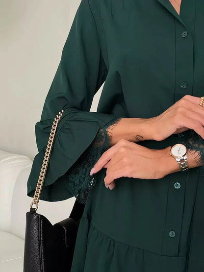 Close-up of a woman's hand in a deep emerald dress with lace cuffs, showcasing elegance and style.
