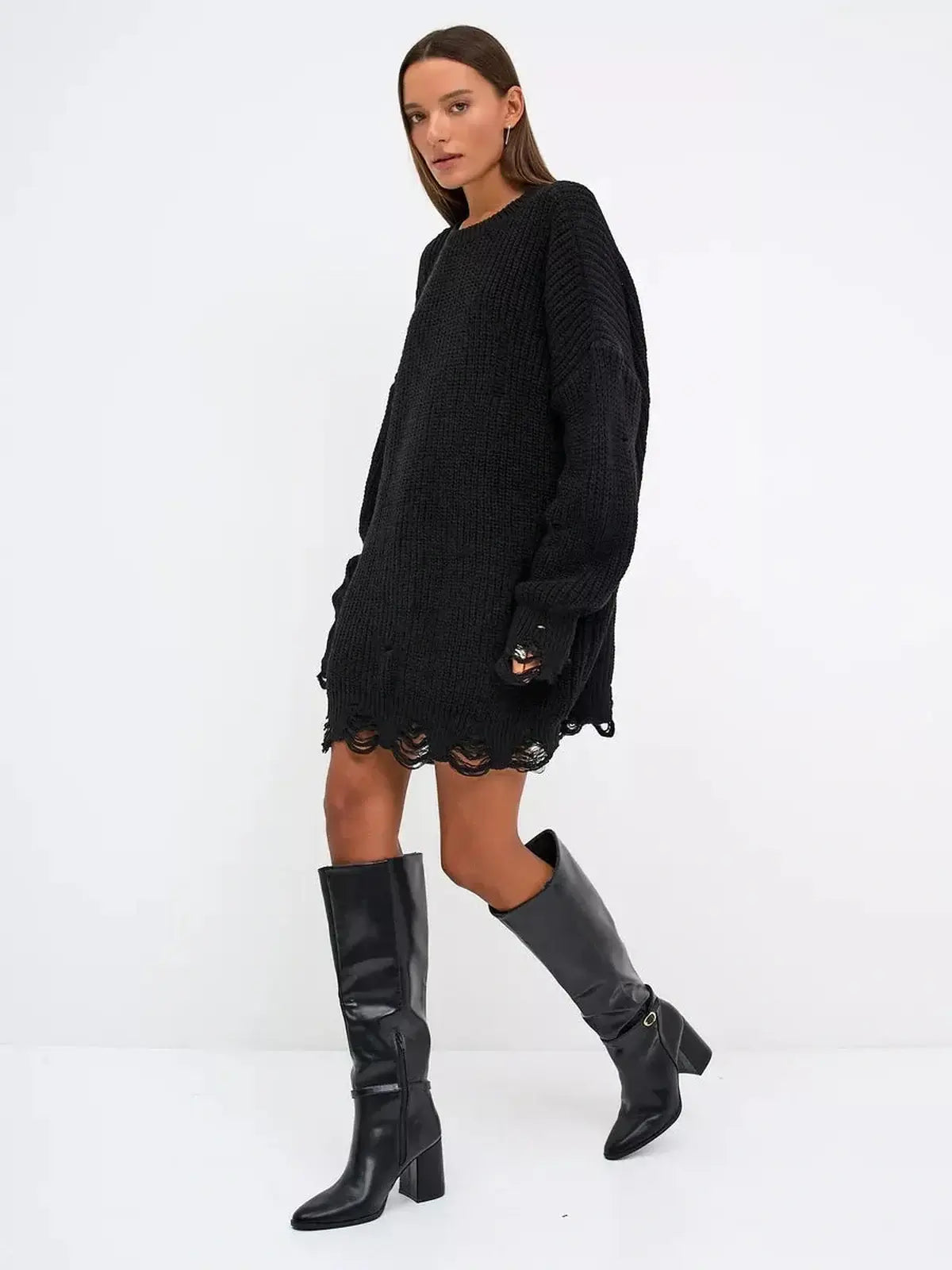 Oversized black knit mini dress with distressed texture, paired with chic knee-high black boots.