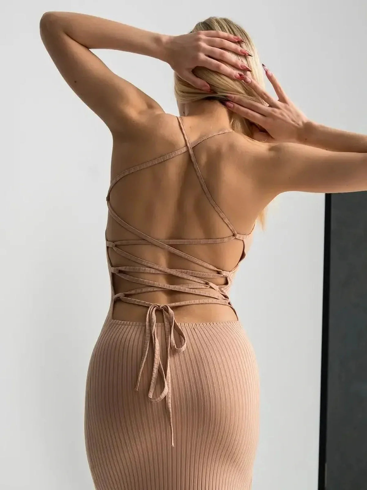 Back view of a model in a nude lace midi dress showcasing a corset lace-up detail.