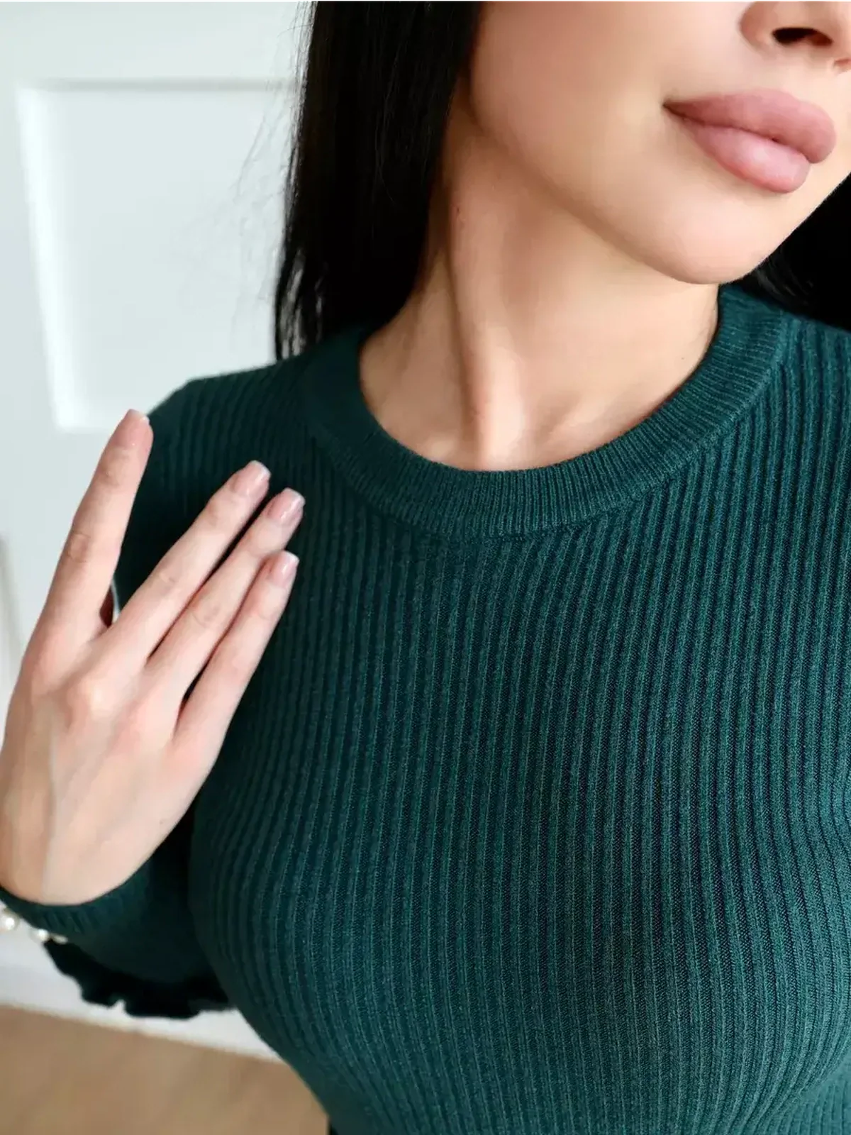 Close-up of a woman wearing the ribbed knit Emerald Grace Midi Dress in emerald green, showcasing its elegant texture and neckline.