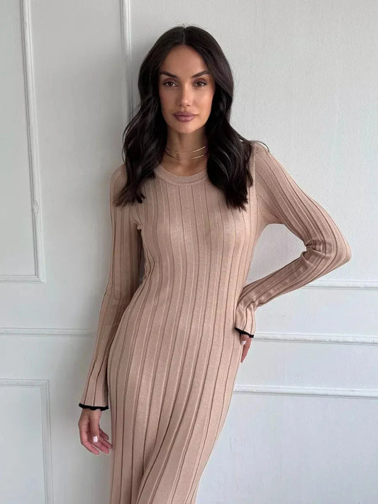 A model showcasing the Sahara Curve Maxi Dress in sandstone beige, featuring a soft ribbed texture and elegant silhouette.