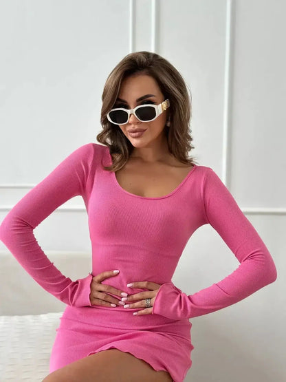 Model wearing a vibrant pink crush mini dress with long sleeves and playful lettuce-edge hem.