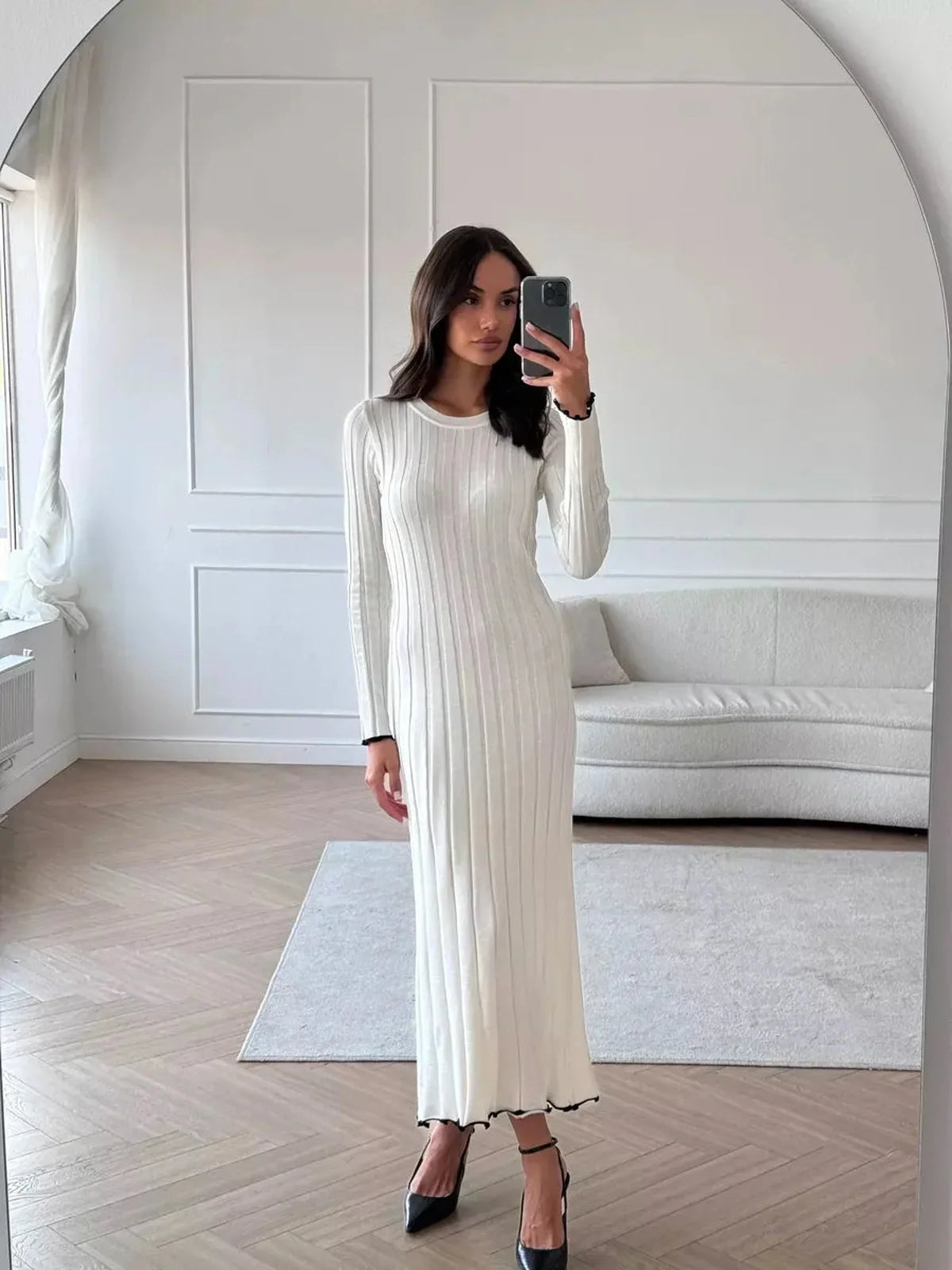 Model wearing an Ivory Grace Maxi Dress, showcasing its elegant ribbed texture and long sleeve design in a chic indoor setting.