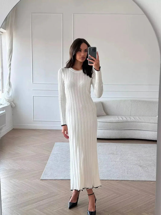 Model wearing an Ivory Grace Maxi Dress, showcasing its elegant ribbed texture and long sleeve design in a chic indoor setting.