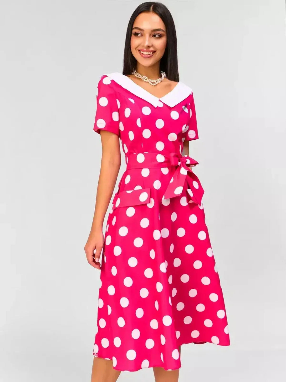 Monaco Charm Midi Dress in pink with white polka dots, featuring a collar and tie waist for a chic retro look.