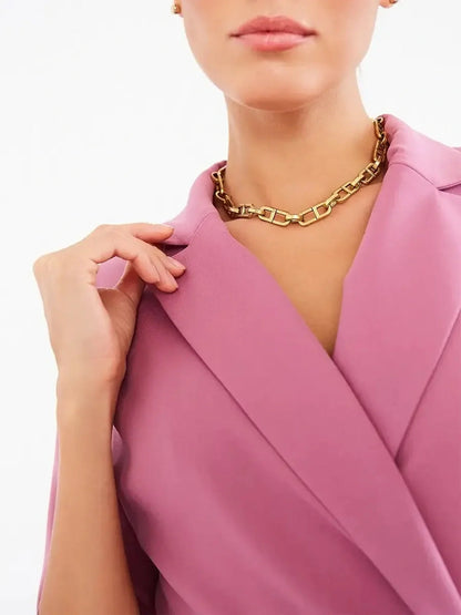 Close-up of a woman wearing a blush wrap midi dress with a gold chain necklace, showcasing chic sophistication.