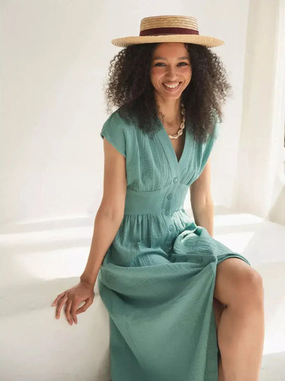 Model wearing a sea-green Veranda midi dress featuring a corset waist and V-neckline, perfect for summer outings.