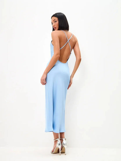Woman wearing an open back icy glow midi dress in light blue, showcasing crisscross straps and elegant silhouette.