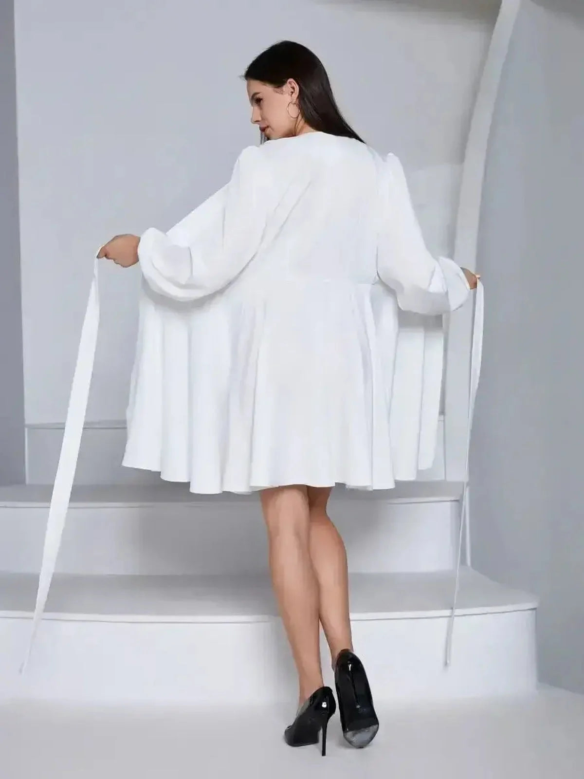 Model showcasing the Ivory Whisper white dress with a flared design and adjustable waist tie, perfect for summer or weddings.