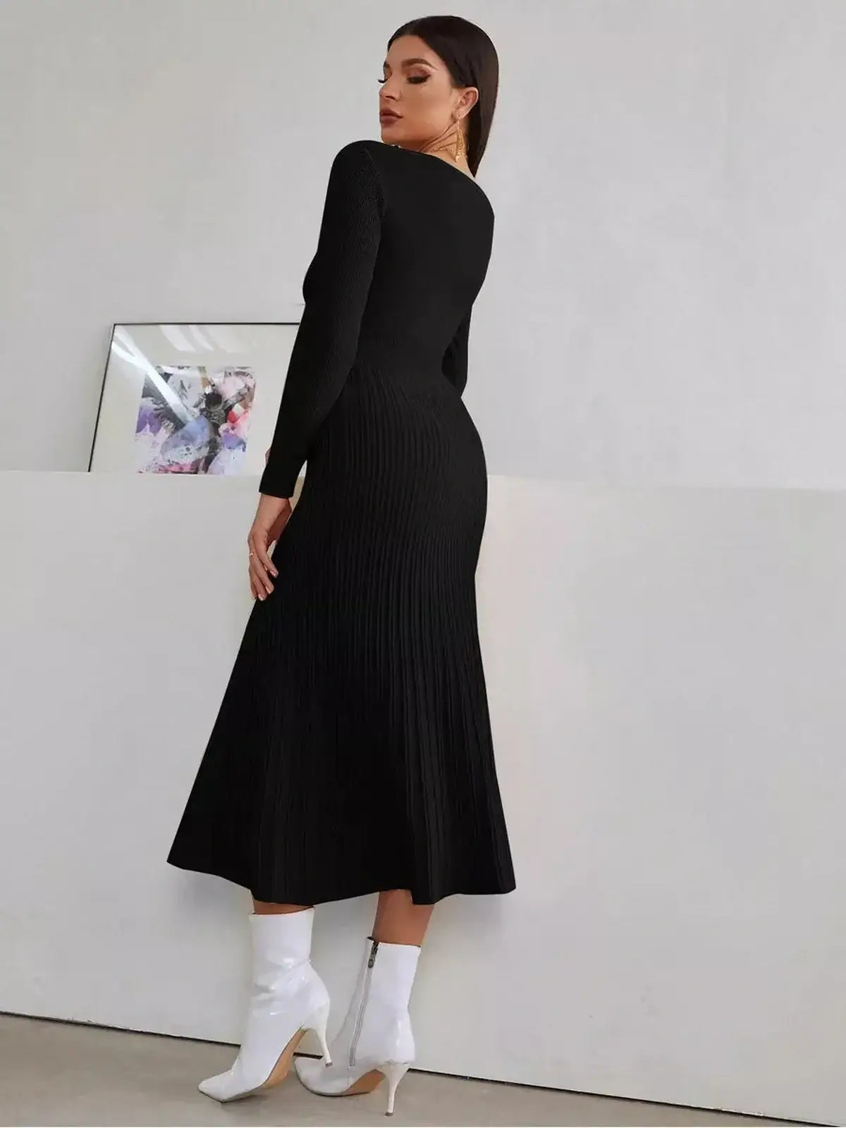 Back view of a woman in a black midi dress with ribbed texture and long sleeves, styled with white ankle boots.