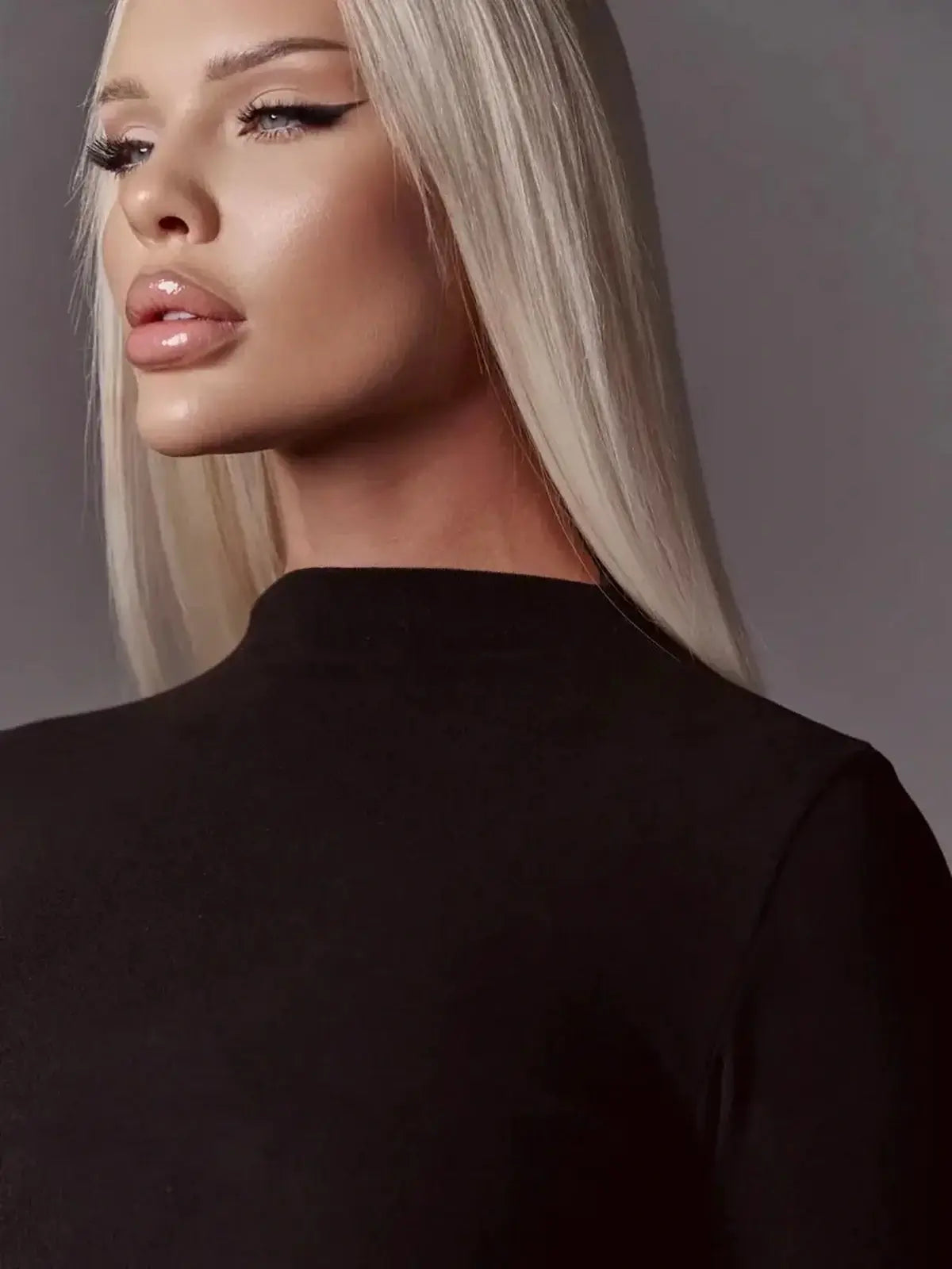 Close-up of a model showcasing the elegant high neck of a black mini dress with dramatic styling.