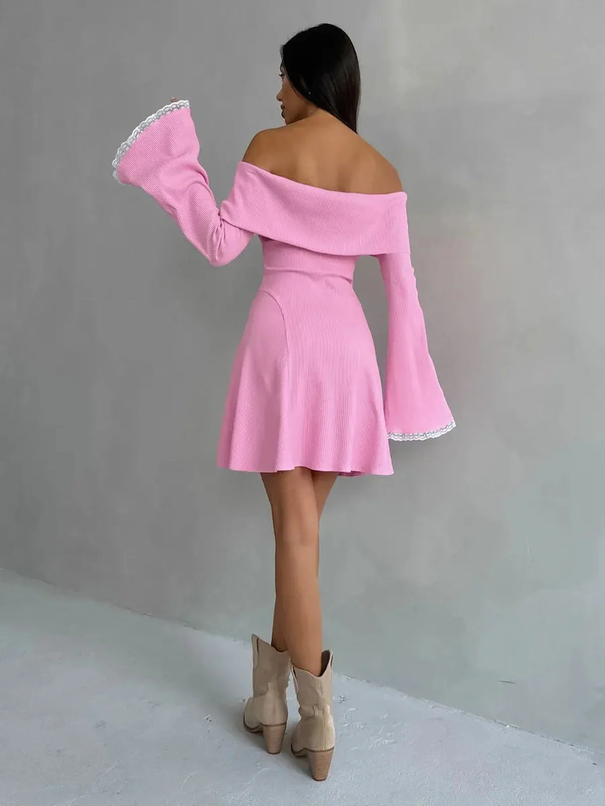Back view of a woman in a pink off-shoulder mini dress with flared sleeves, perfect for summer events or weddings.