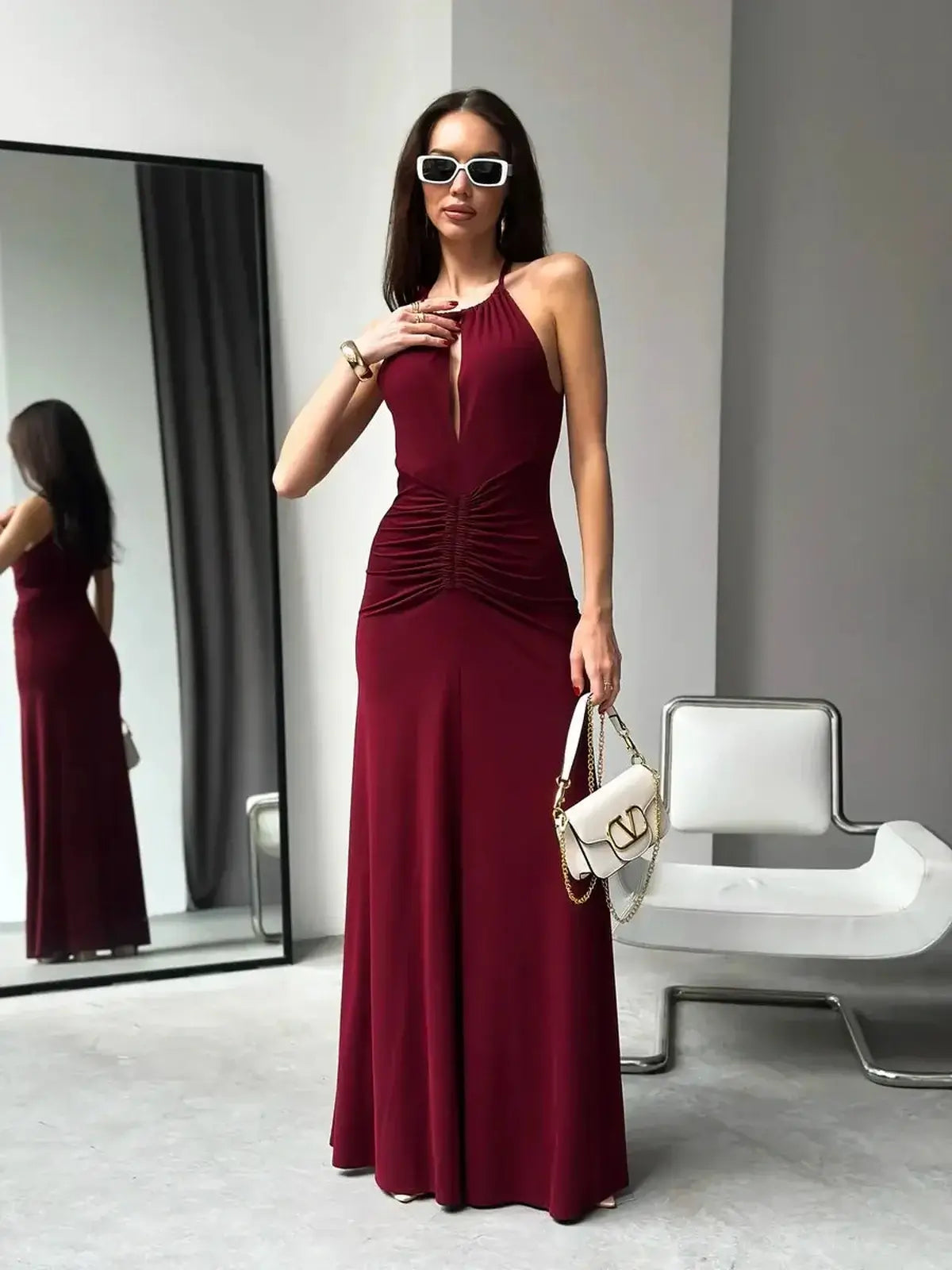Elegant burgundy maxi dress with draped halter neckline and ruching at the waist, perfect for formal occasions.