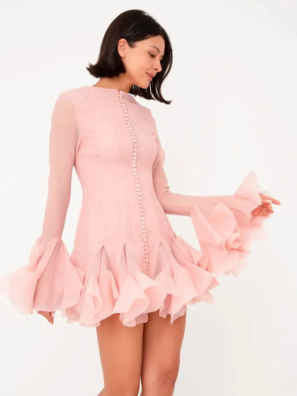 Model wearing a pink chiffon Rose Whirl Mini Dress with flounced sleeves and pleated hem, perfect for weddings and parties.