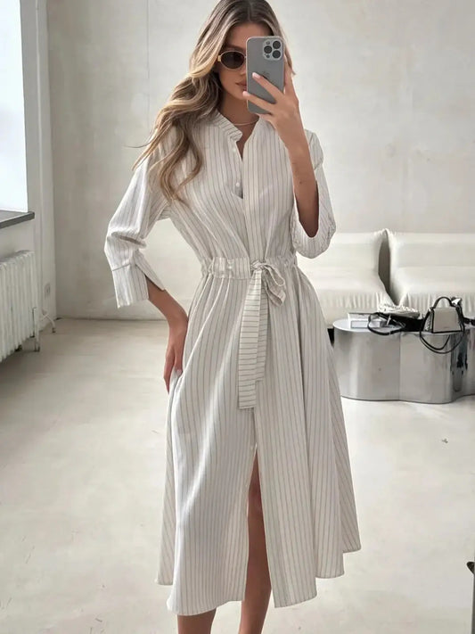 Elegant pinstripe midi dress with waist tie and front slit, perfect for business casual or summer outings.