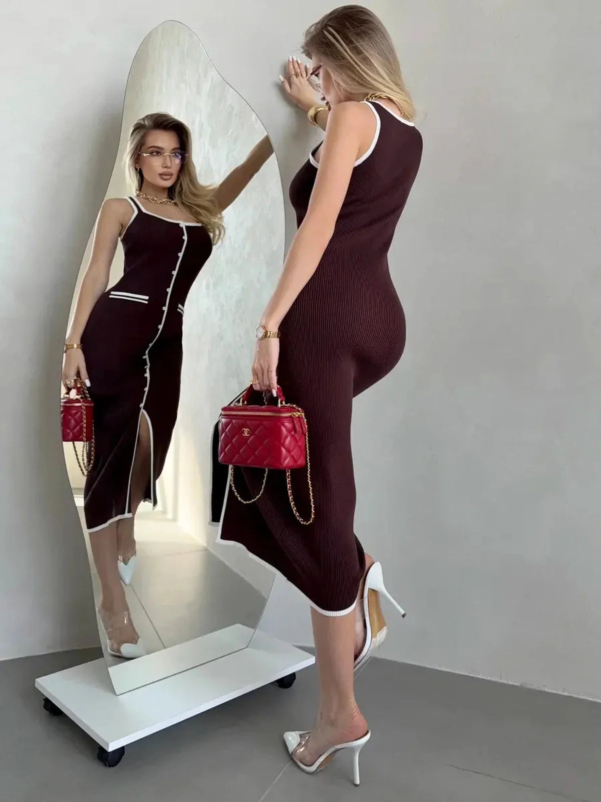 Woman modeling Cocoa Button Midi Dress with chic white trim, showcasing its elegant silhouette by a mirror.