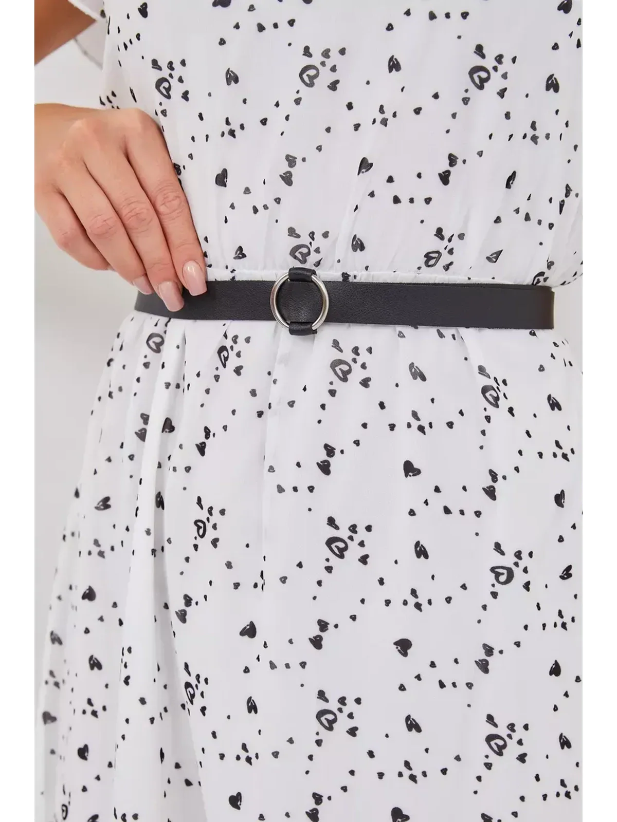 Close-up of a black belt cinching the waist of a white mini dress with an abstract print.
