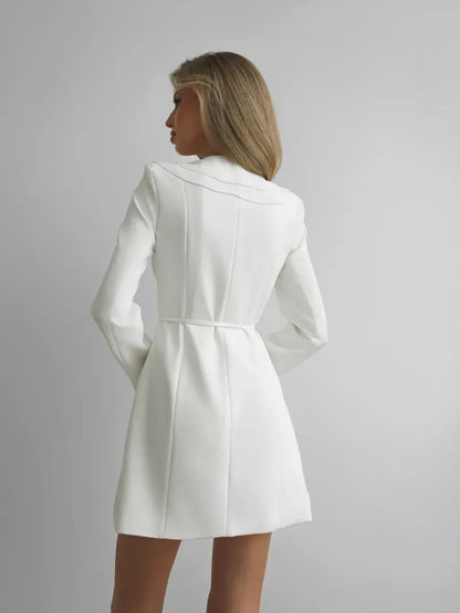 Back view of a woman in a white mini dress showcasing tailored structure and long sleeves, perfect for formal occasions.
