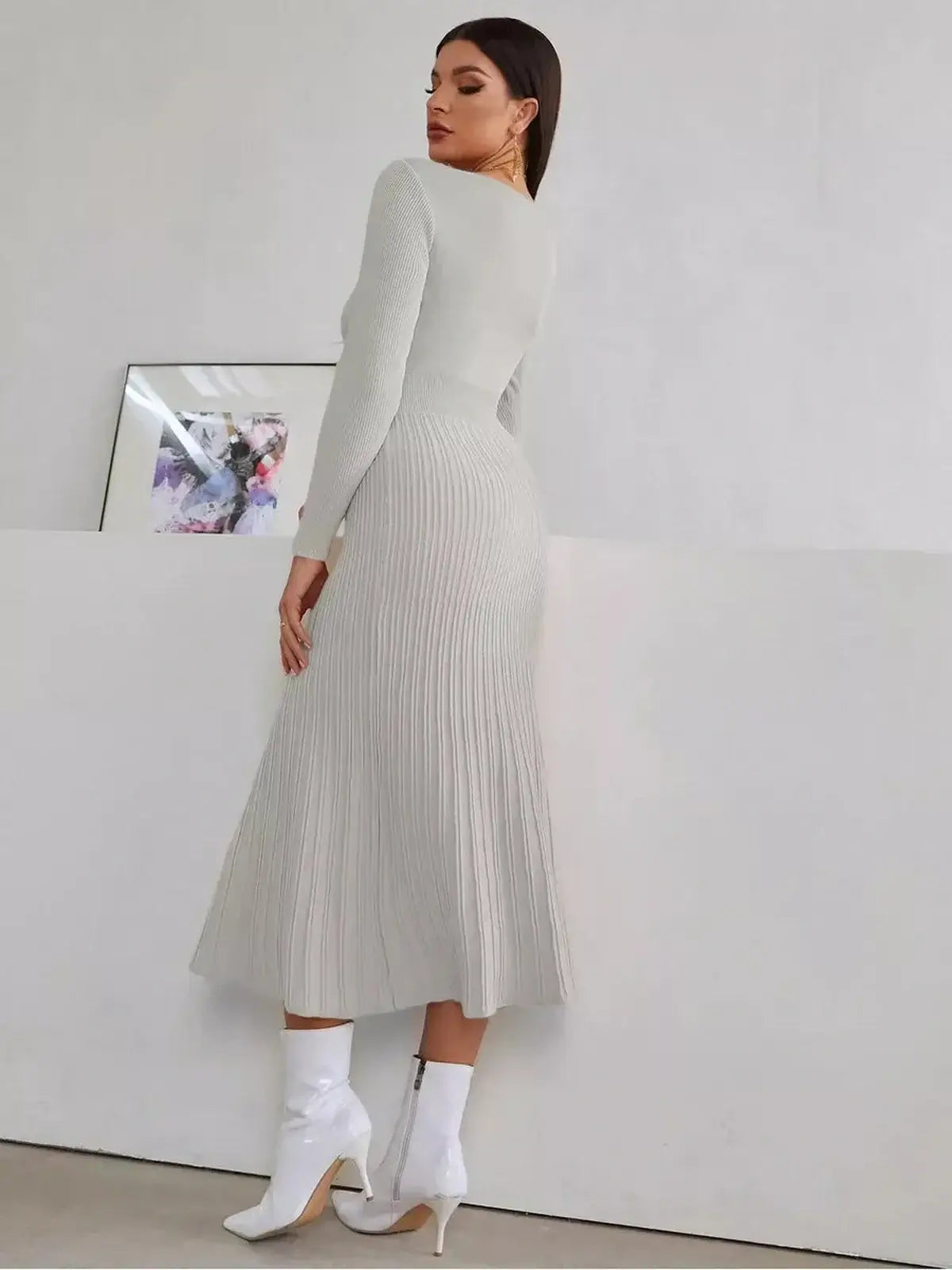 Woman in a sculpted grey midi dress, showcasing ribbed texture and pleated skirt, perfect for wedding guest or formal occasions.