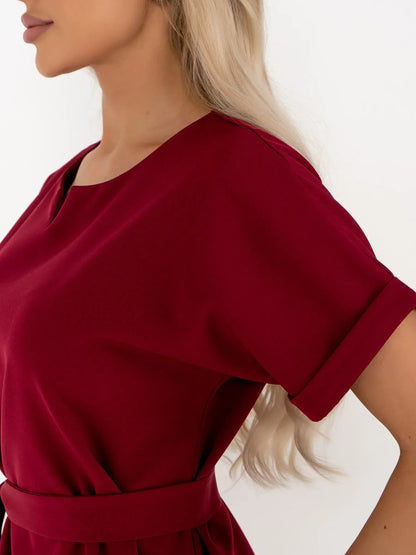 Close-up of a woman wearing a crimson mini dress featuring a structured sheath silhouette and short sleeves.