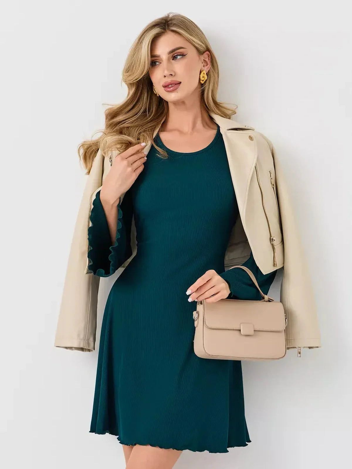Woman wearing the Emerald Whisper mini dress in emerald green, styled with a stylish jacket and handbag.