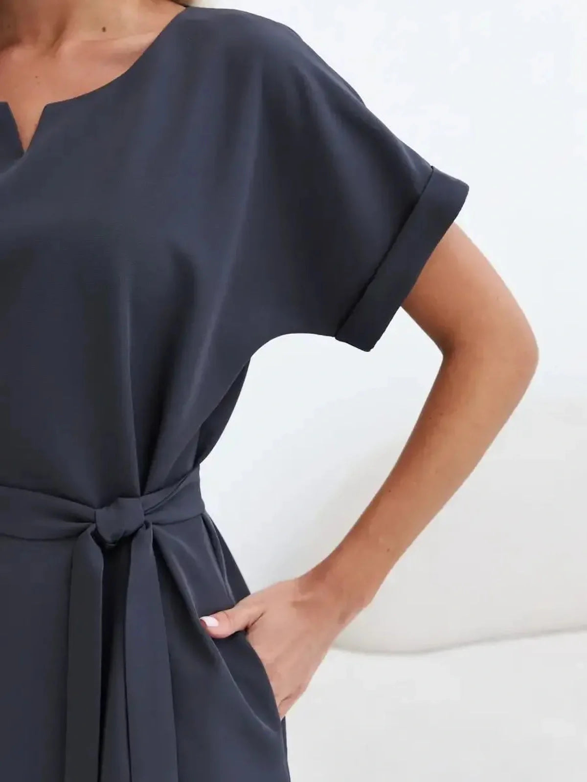 Close-up of a stylish graphite mini dress featuring short sleeves and a belted waist for a flattering fit.