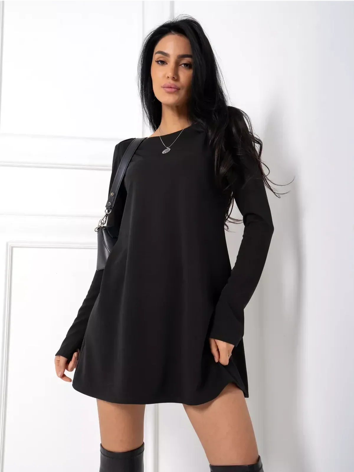 Model showcasing the Midnight Flow black mini dress with long sleeves and a minimalist design, ideal for modern occasions.