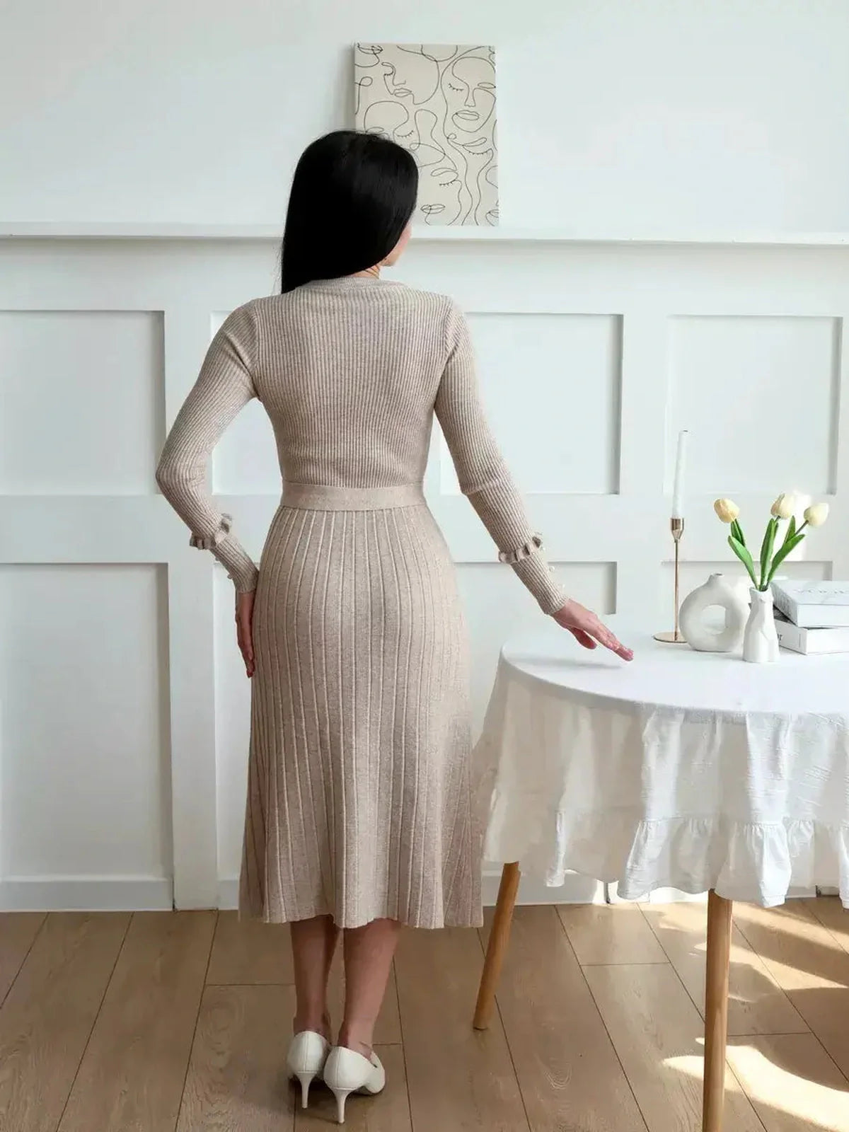 Back view of a woman in a beige ribbed knit midi dress, showcasing its elegant silhouette and fitted waist.