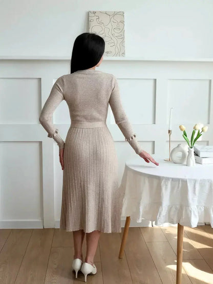 Back view of a woman in a beige ribbed knit midi dress, showcasing its elegant silhouette and fitted waist.