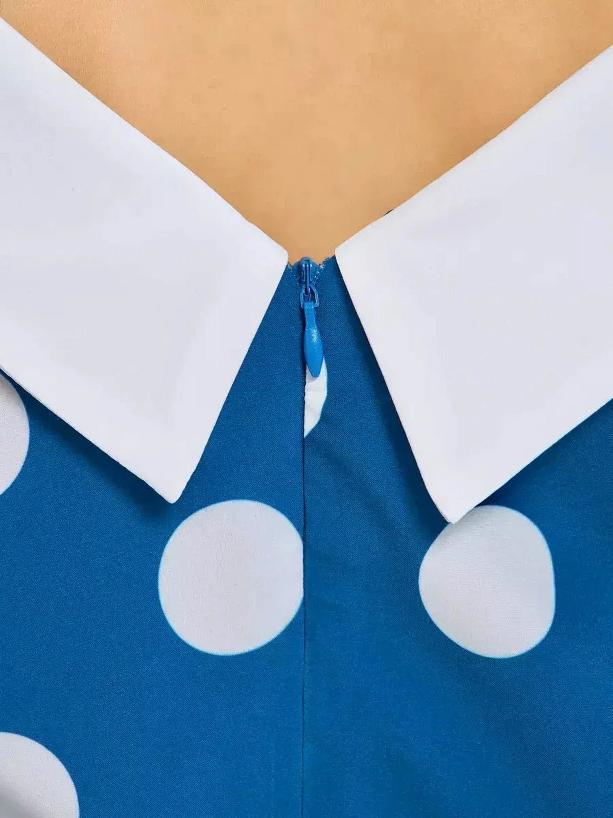 Close-up of the Pearl Dot Midi Dress showcasing the wide white collar and zip detail on a dark teal fabric with polka dots.