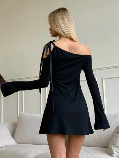 Back view of a chic black Sculpted Edge Mini Dress with asymmetric neckline and flared long sleeves.