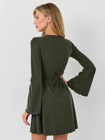 Model showcasing the Ivy Bell mini dress with flared bell sleeves and a tied waist in an olive green color.
