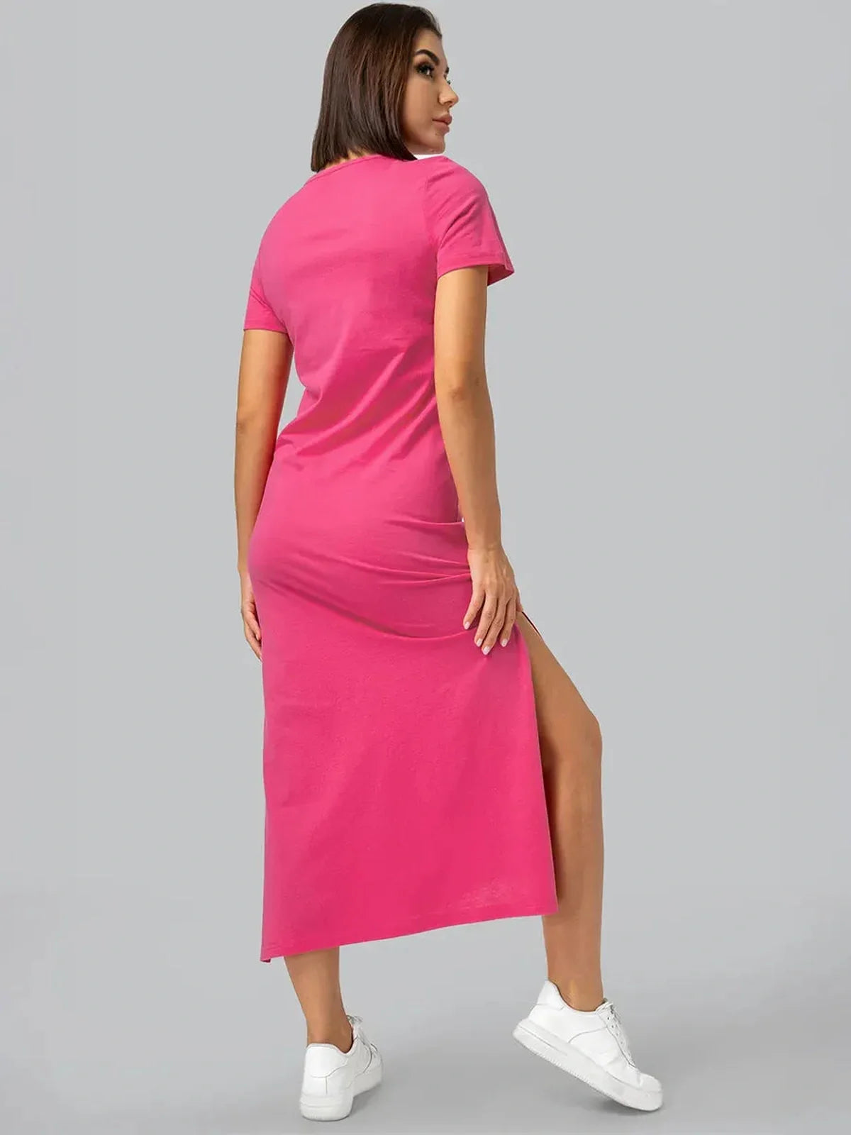 Back view of a woman wearing a pink Breeze Midi Dress with playful side slits and short sleeves, perfect for summer occasions.