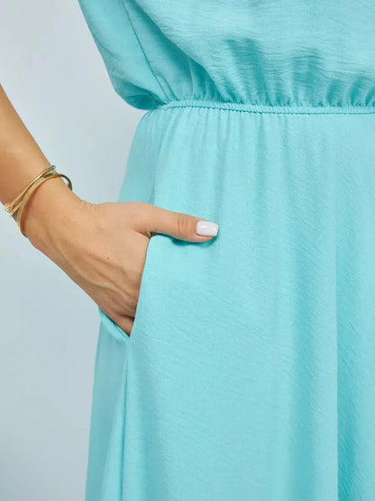 Close-up of a hand in the pocket of a light blue maxi dress, highlighting the elegant design and fabric.