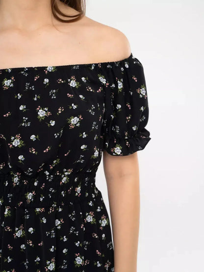 Close-up of a woman wearing the Midnight Bloom black floral dress with off-shoulder neckline and puff sleeves.