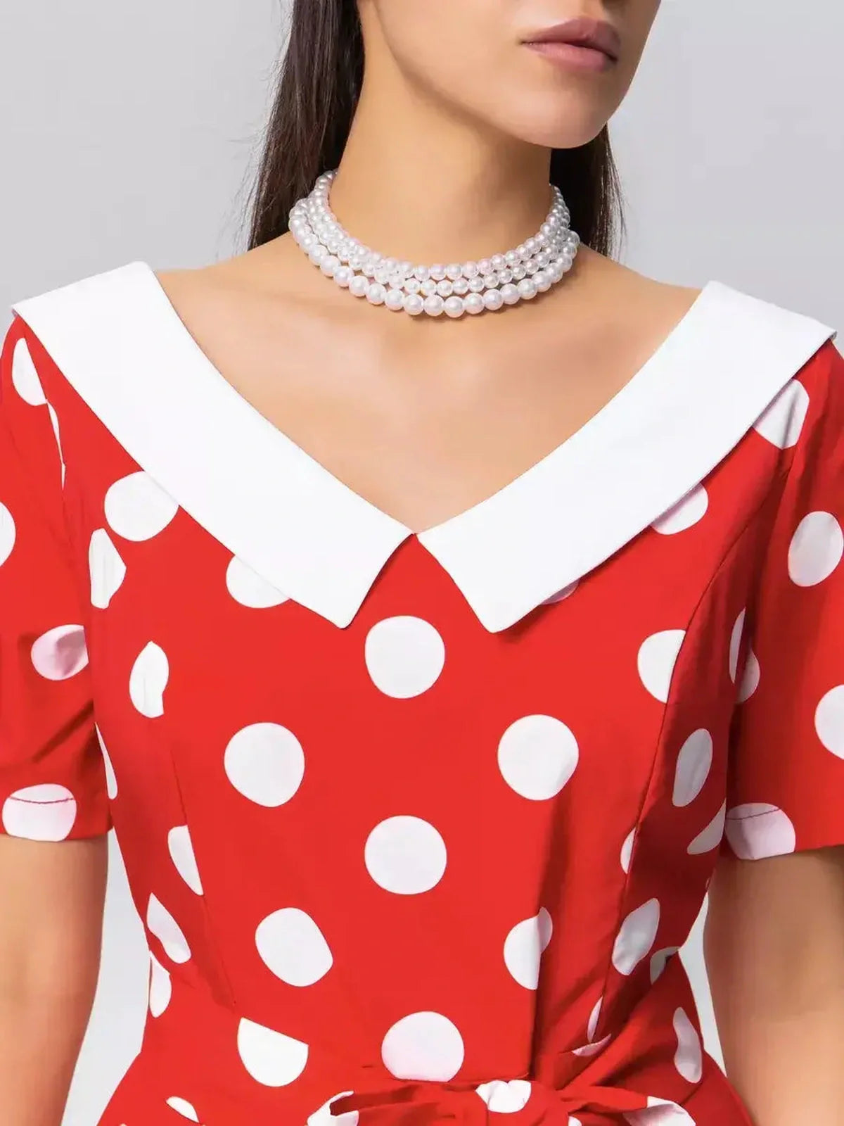 Close-up of the Retro Charm Midi Dress featuring red polka dots, a white collar, and a stylish tie belt for vintage elegance.
