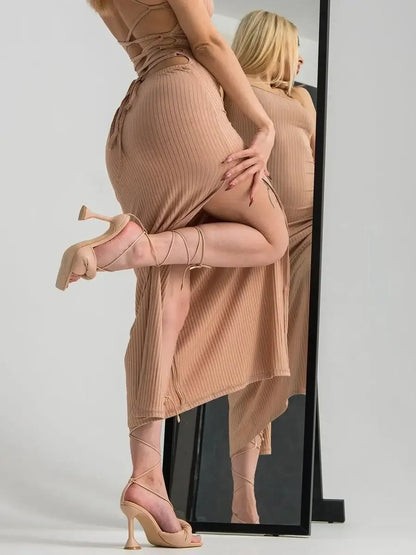 Model showcasing a nude lace midi dress with a corset back and strappy heels in front of a mirror.