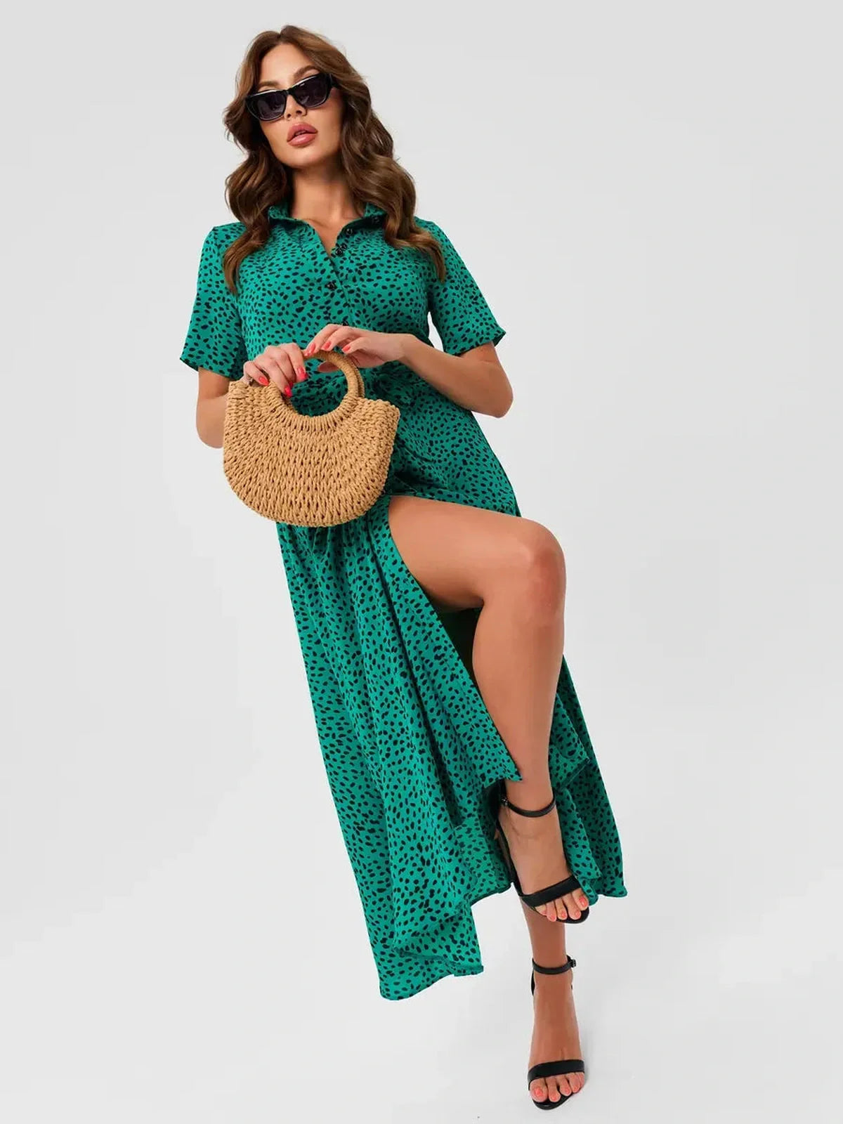 Model wearing a vibrant jade petal midi dress with a slit, holding a straw bag and wearing sunglasses.