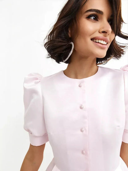 Woman smiling in a pink Pearl Puff Mini Dress with satin finish and puff sleeves, perfect for cocktail or wedding guest attire.