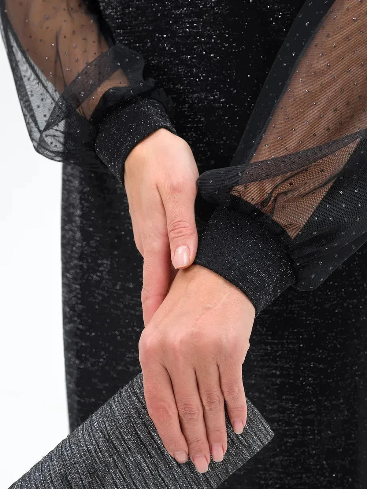 Close-up of hands wearing sheer sleeves of Lurex Aura Midi Dress, showcasing elegance and detail with a clutch.