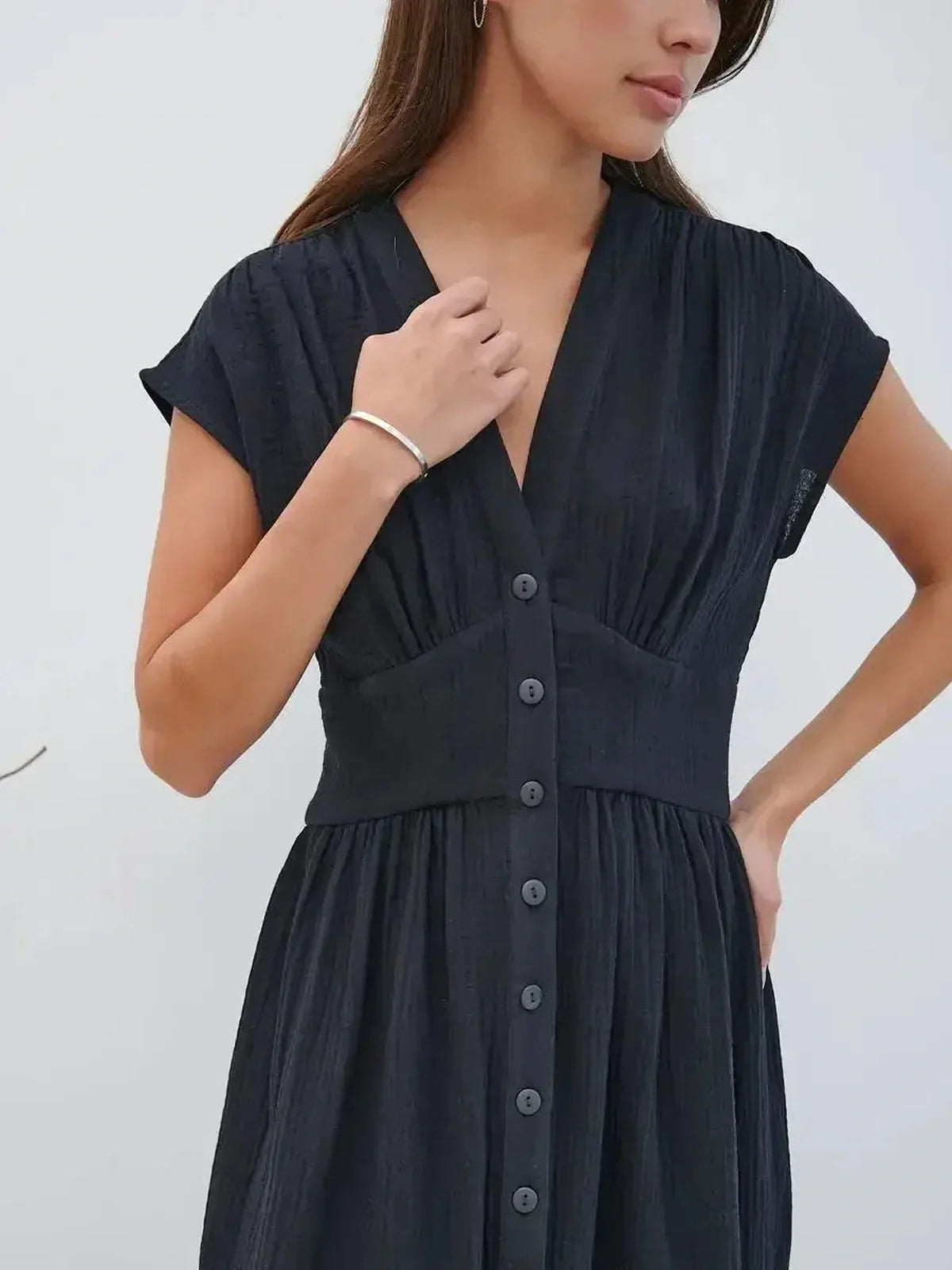 Close-up of a woman wearing the Sable Grace Midi Dress, showcasing its V-neck, sculpted waist, and button detail.
