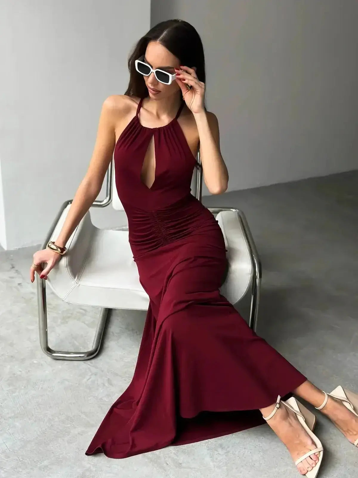 Elegant women in a burgundy maxi dress with halter neckline and ruched waist, featuring a front keyhole detail.