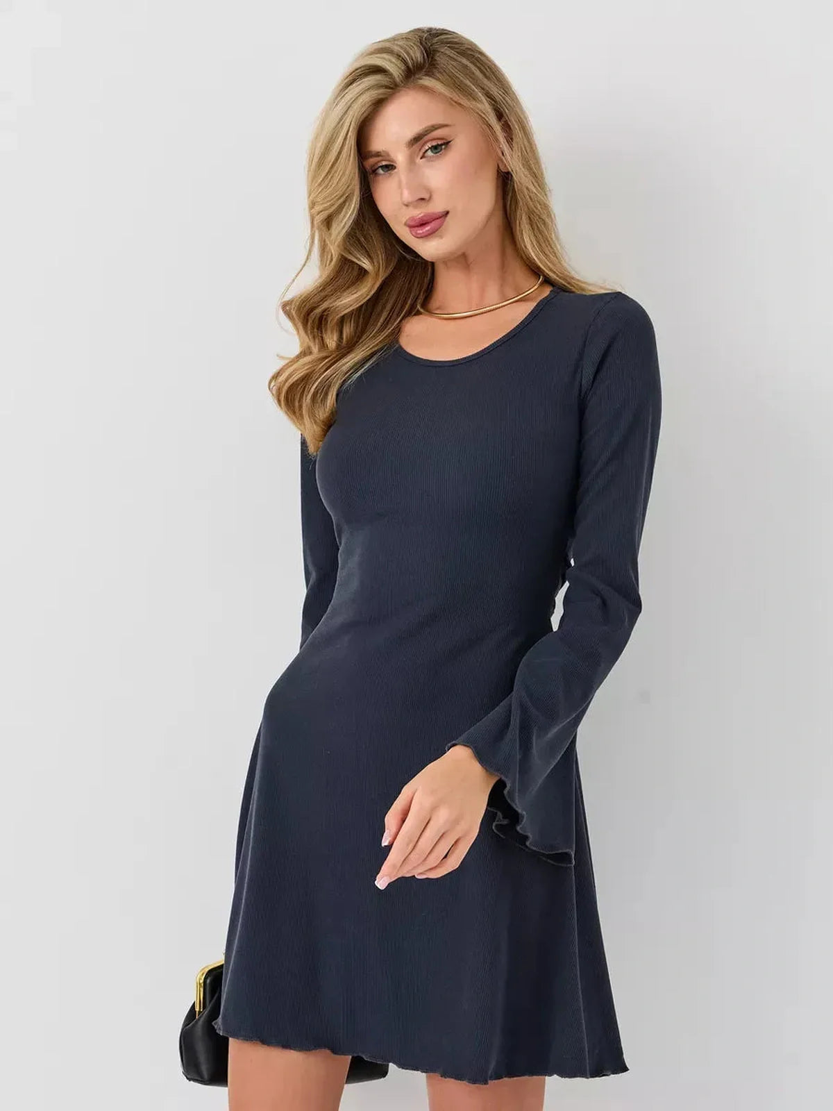 Woman wearing a stylish black mini dress with long sleeves and flared cuffs, perfect for casual outings.
