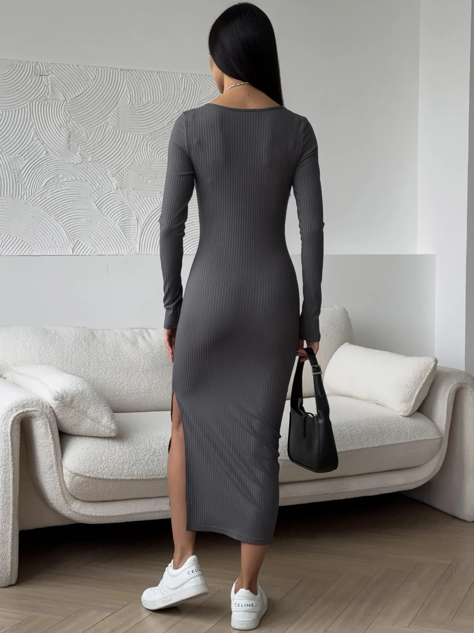 Back view of a woman in a sleek gray midi dress showcasing a thigh-high slit and paired with white sneakers.