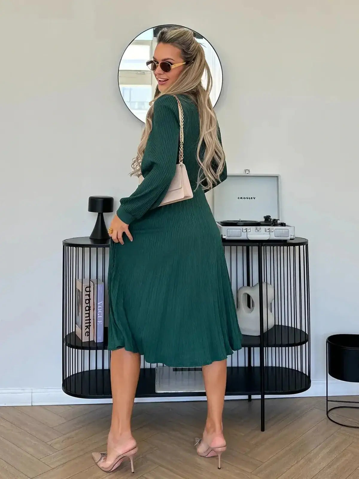 Model showcasing the Emerald Poise Midi Dress in a rich green color, styled with sunglasses and a chic handbag.